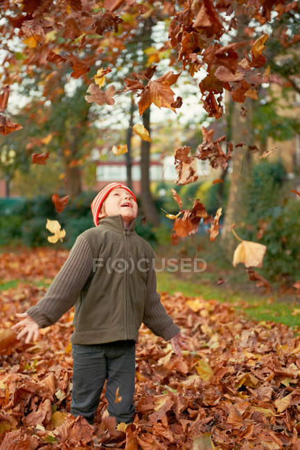 Ragazzo che gioca in foglie d'autunno — Foto stock