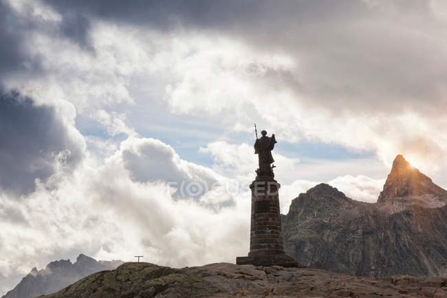 Ornate statue on rocky mountaintop with cloudy sky — Stock Photo