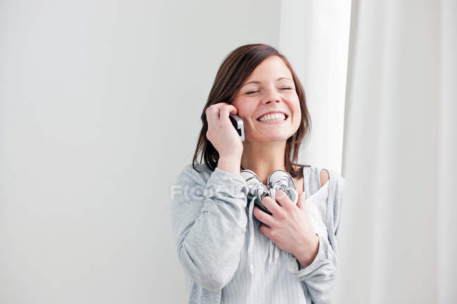 Woman on cell phone holding baby shoes — Stock Photo