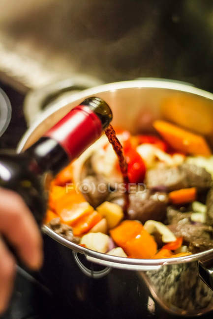 Man pouring wine into vegetables — Stock Photo