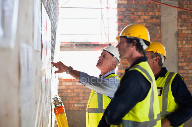 Trabajadores que leen planos en el sitio - foto de stock