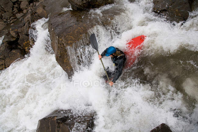 Hombre paseando en canoa sobre cascada rocosa - foto de stock