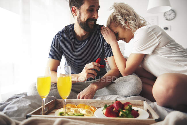 Man proposing with open ring box to woman in bed — Stock Photo