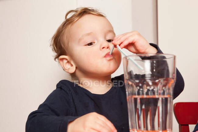 Мальчик пьет воду с соломой — стоковое фото
