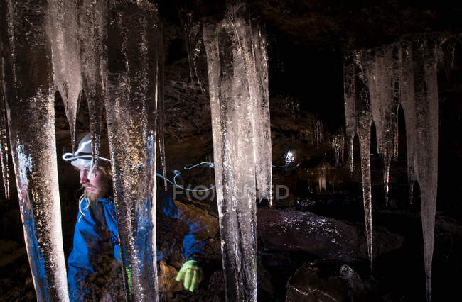 Hiker with icicles in glacial cave — Stock Photo