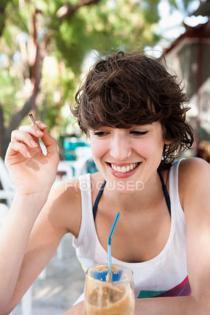 Lächelnde Frau trinkt durch Stroh — Stockfoto