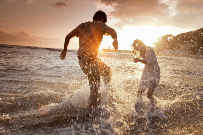 Couple jouant dans les vagues à la plage — Photo de stock