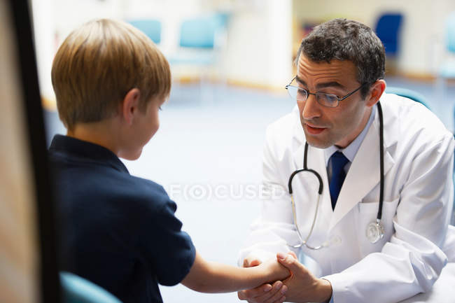 Médico examinando joven chico - foto de stock