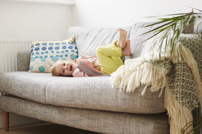 Retrato de criança feminina brincando no sofá da sala de estar — Fotografia de Stock