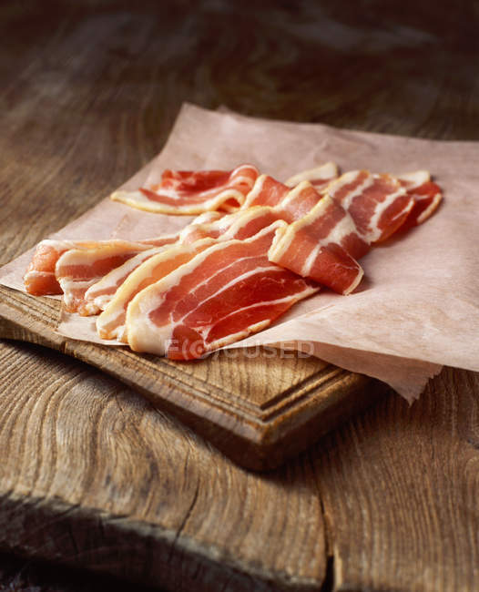 Rashers de bacon entremeado cru em papel de cozedura — Fotografia de Stock