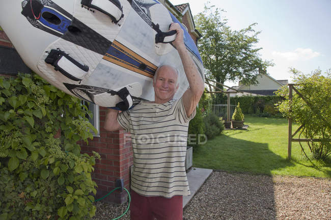 Старший чоловік, що носить дошку для серфінгу — стокове фото