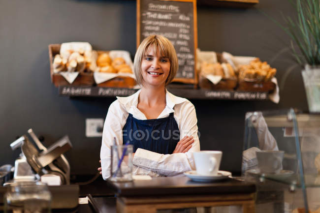 Smiling woman working in cafe, focus on foreground — Stock Photo