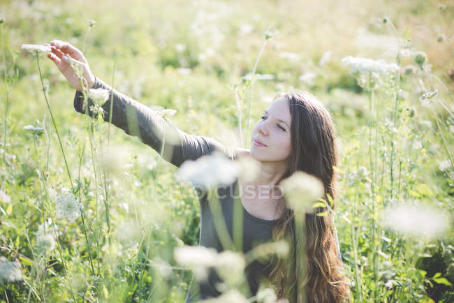 Jovem mulher colhendo flores selvagens no campo — Fotografia de Stock