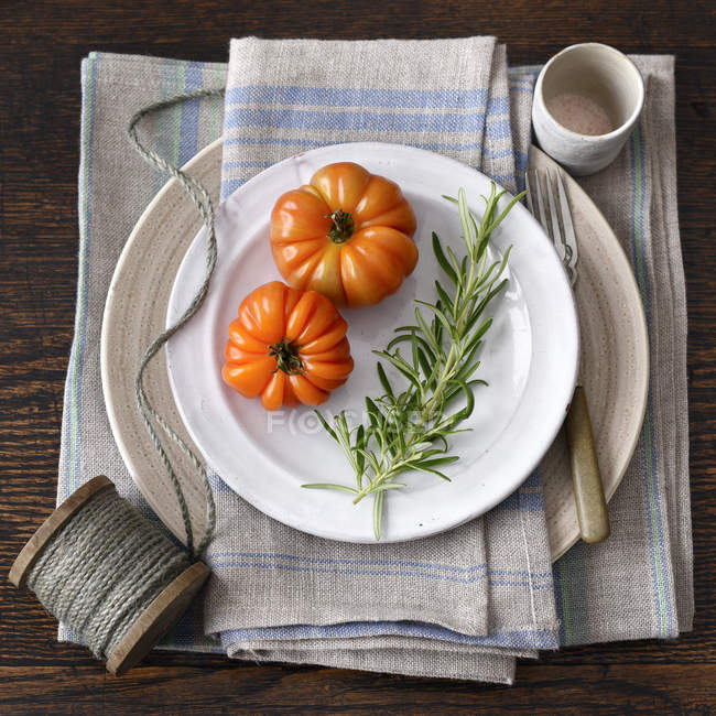 Tomatoes with rosemary on plates — Stock Photo
