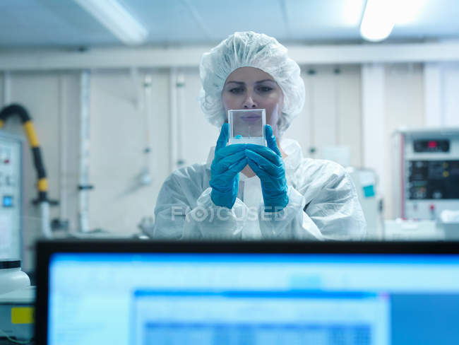 Female scientist wearing protective clothing in a laboratory, holding a fusion target — Stock Photo