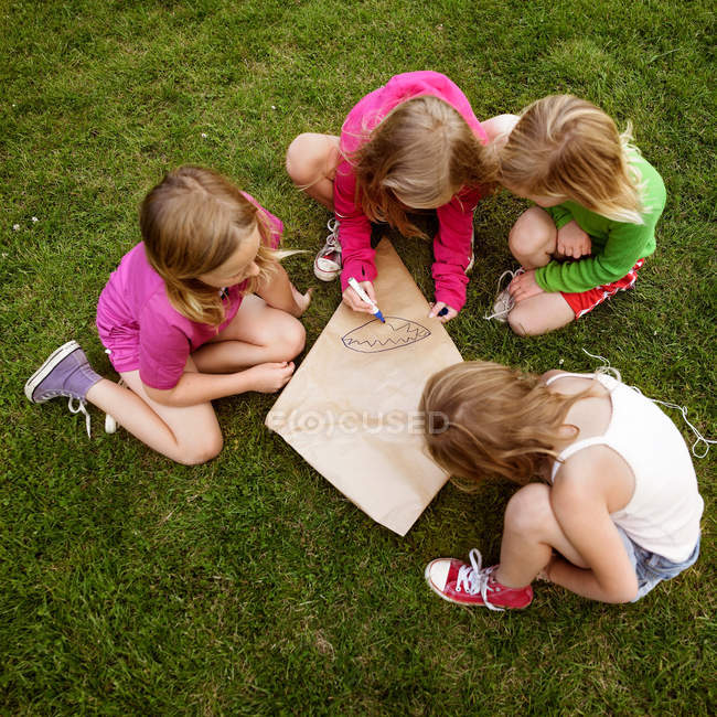 Erhöhte Ansicht von Mädchen, die Drachen auf Gras machen — Stockfoto