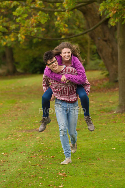 Man carrying woman in park, focus on foreground — Stock Photo