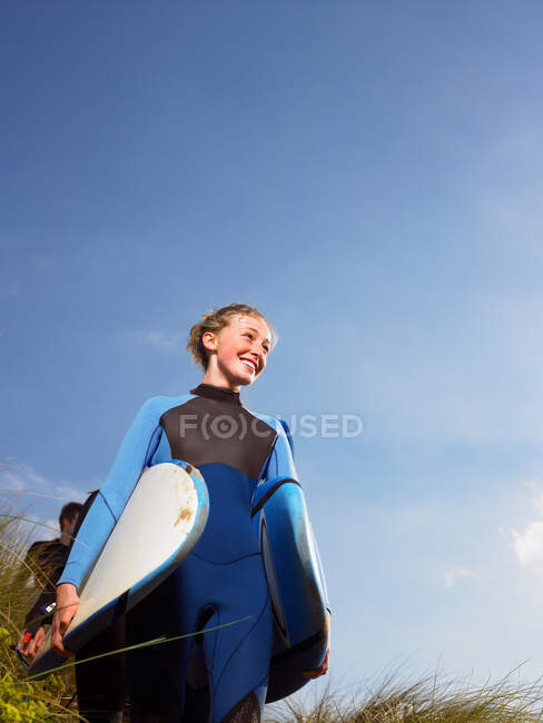 Surfista feminina caminhando através da grama — Fotografia de Stock