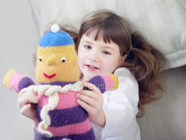 Girl playing with stuffed animal on sofa — Stock Photo