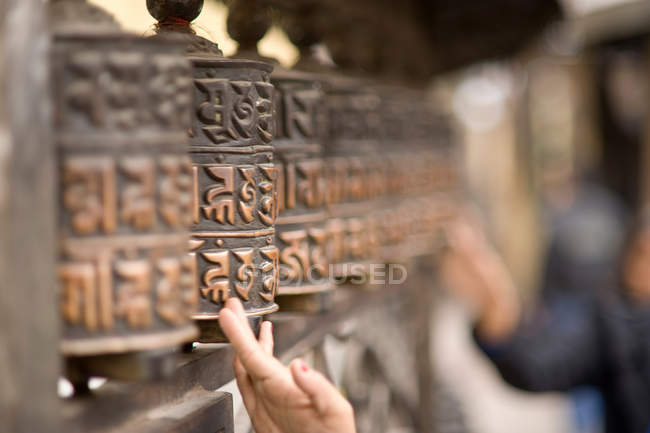 Hands touching carved wooden poles — Stock Photo