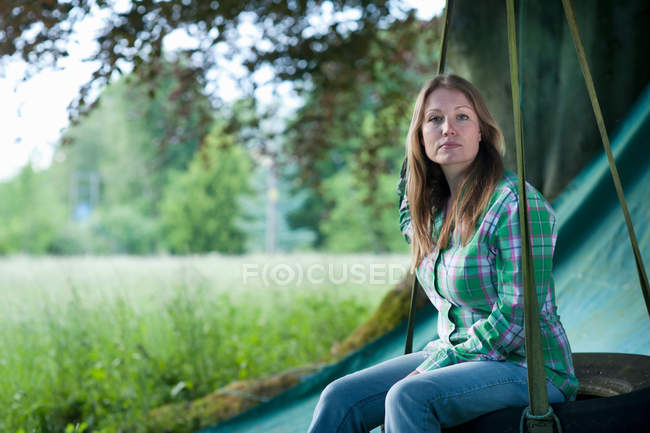 Woman sitting in tire swing outdoors — Stock Photo