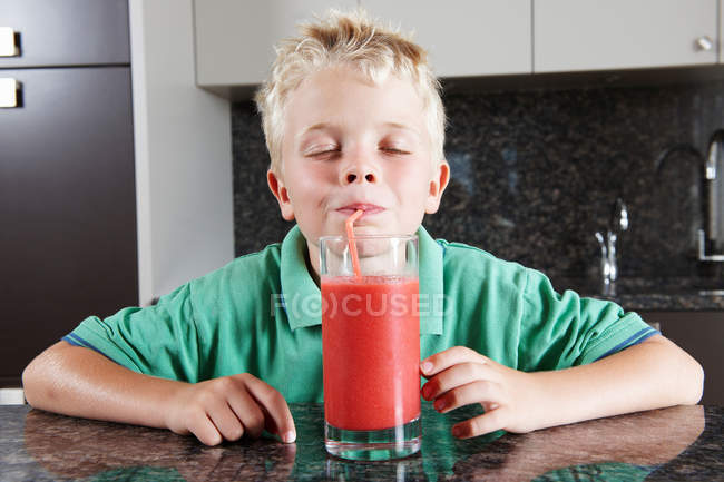 Menino bebendo suco de frutas com palha — Fotografia de Stock
