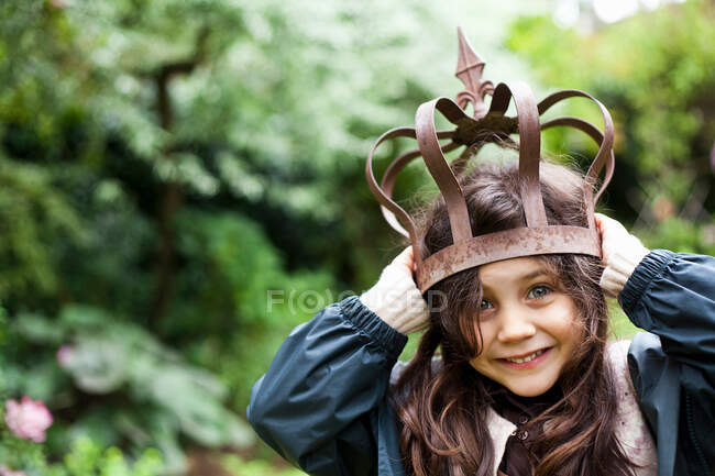 Girl playing with metal crown outdoors — Stock Photo
