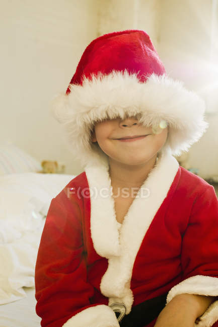 Портрет маленького мальчика, спрятанного шляпой Санта Клауса — стоковое фото