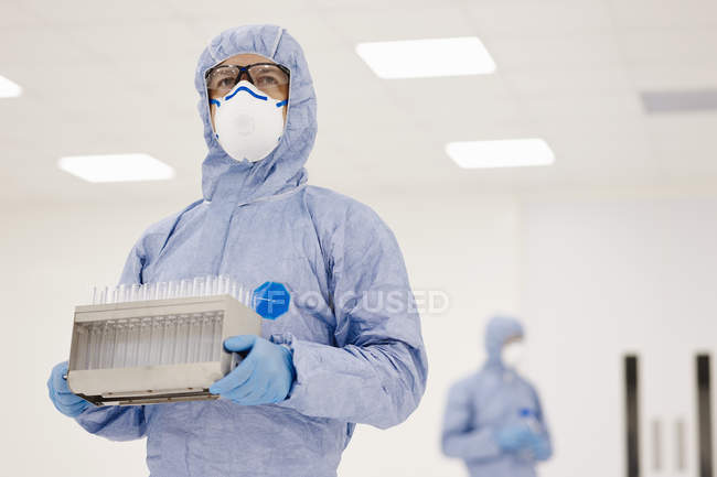 Scientifique portant un plateau d'éprouvettes en laboratoire — Photo de stock