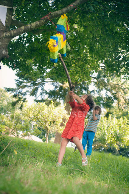 Girl swinging at pinata at party — Stock Photo