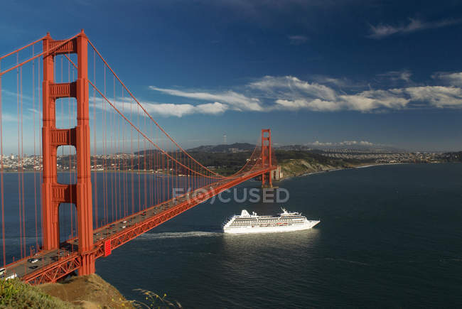 Schiff segelt unter goldener Torbrücke — Stockfoto