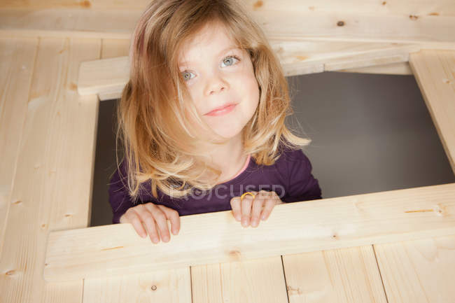 Menina espreitando para fora janela da casa de jogos — Fotografia de Stock