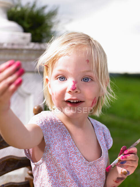 Kleines Mädchen malt in einem grünen Feld — Stockfoto