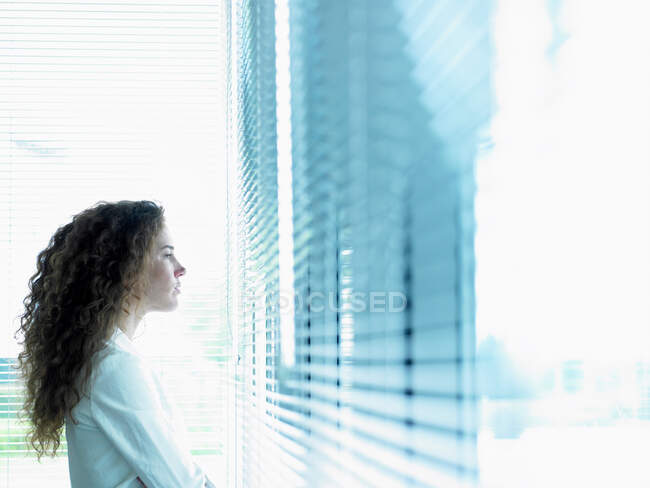 Mujer de negocios mirando por la ventana - foto de stock