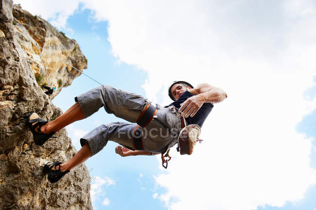 Baixa visão angular do homem penhasco de escalada durante o dia — Fotografia de Stock
