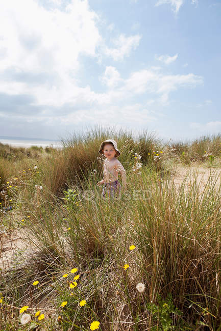 Niño caminando en la arena cubierta de hierba - foto de stock