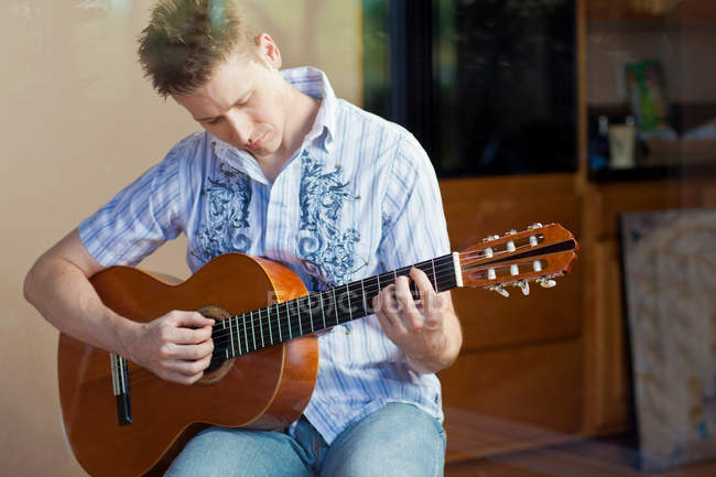 Homme jouant de la guitare dans le salon — Photo de stock
