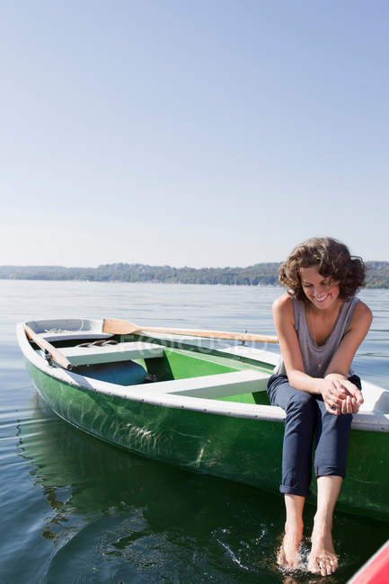 Frau lässt Füße von Boot im See baumeln — Stockfoto