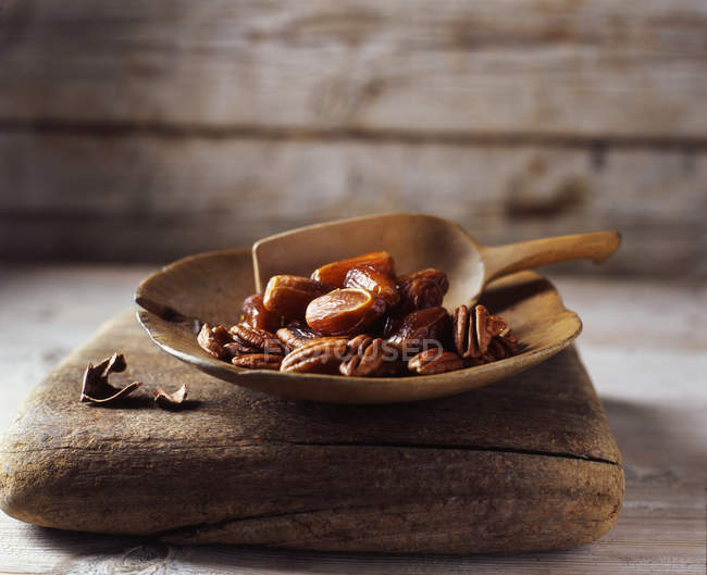 Свидания и грецкие орехи в деревенской деревянной чаше — стоковое фото