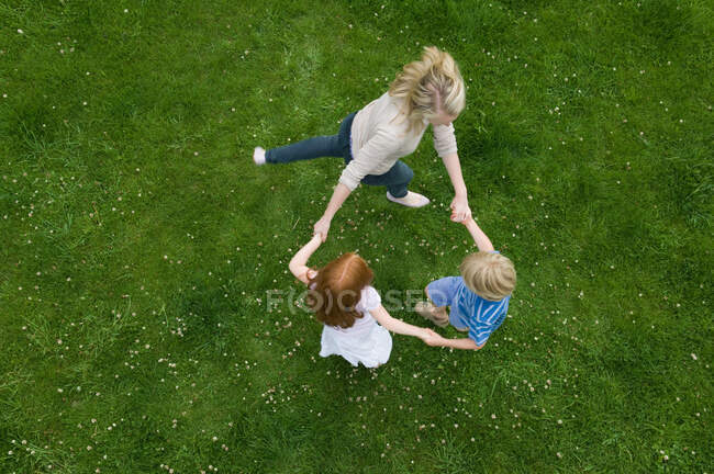 Mother and children playing in grass — Stock Photo