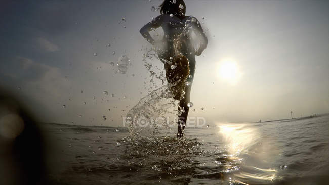 Femme dans l'océan éclaboussant l'eau — Photo de stock