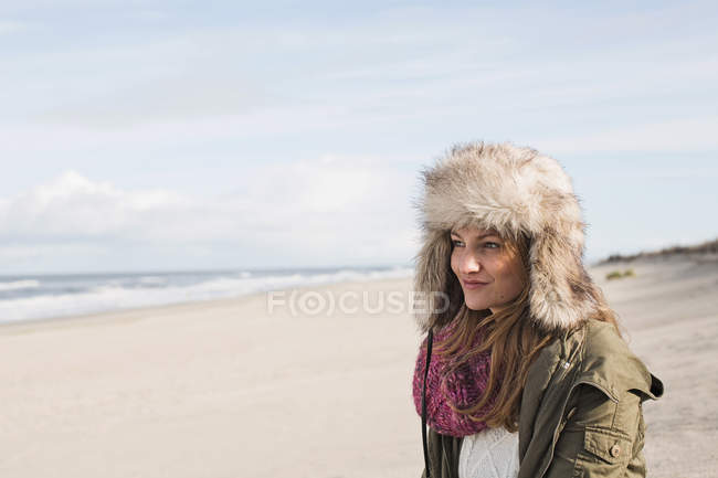 Donna sorridente in piedi sulla spiaggia — Foto stock