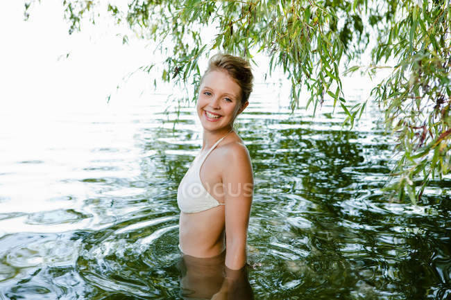 Mujer sonriente vadeando en el río - foto de stock
