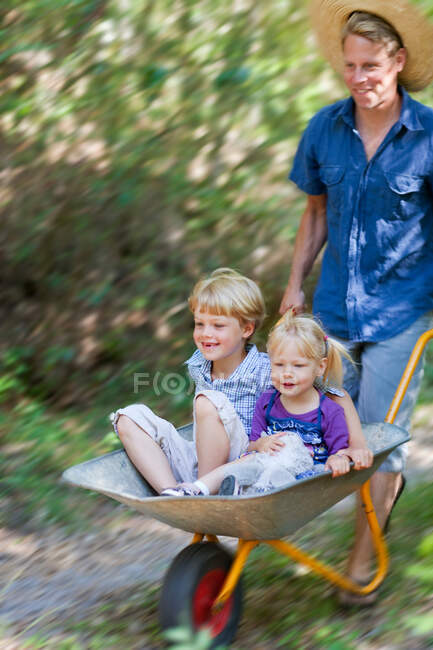 Pai empurrando crianças no carrinho de mão — Fotografia de Stock