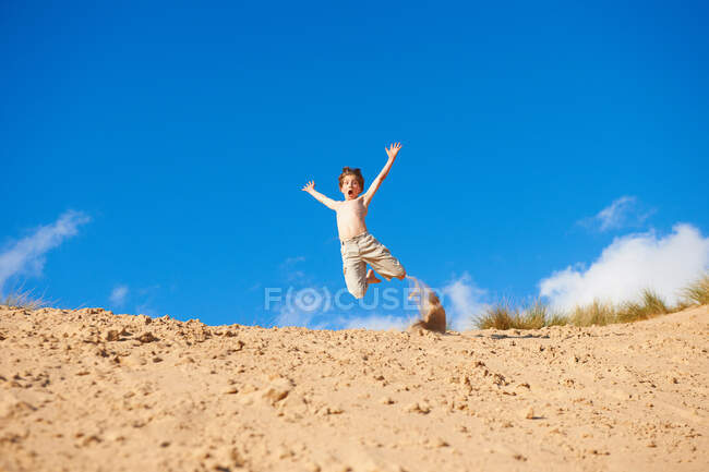 Garçon sauter sur la plage — Photo de stock