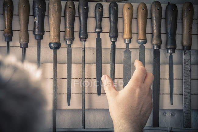 Man taking chisel from rack — Stock Photo