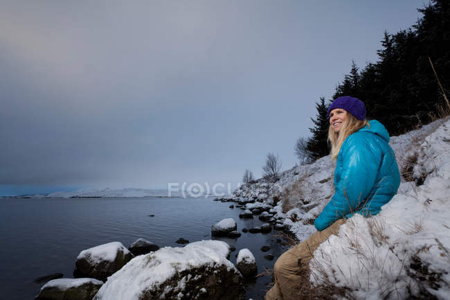 Woman admiring lake in snow — Stock Photo