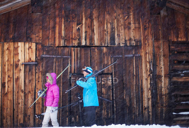 Pareja que lleva esquís y bastones en la nieve - foto de stock