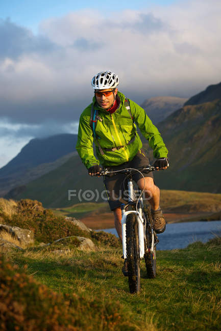 Ciclista de montaña en ladera cubierta de hierba - foto de stock