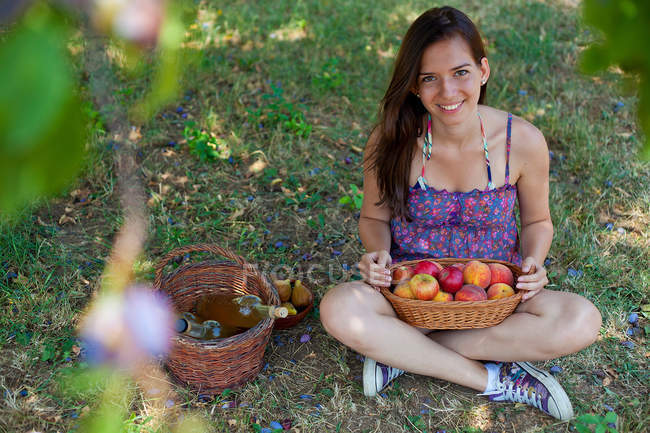 Mujer sonriente de picnic en huerto - foto de stock